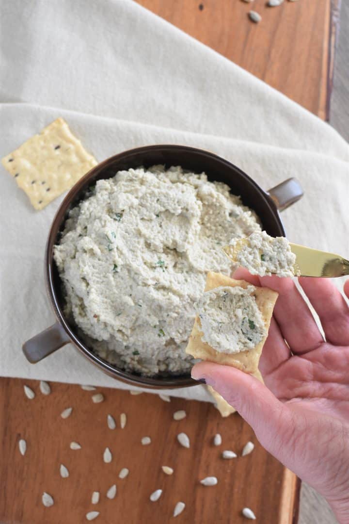 spreading cheese onto a cracker over the bowl of cheese