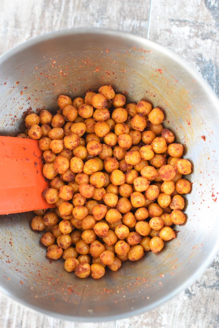 Chickpeas combined with BBQ seasoning in mixing bowl