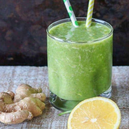 ginger smoothie in a glass with two straws.