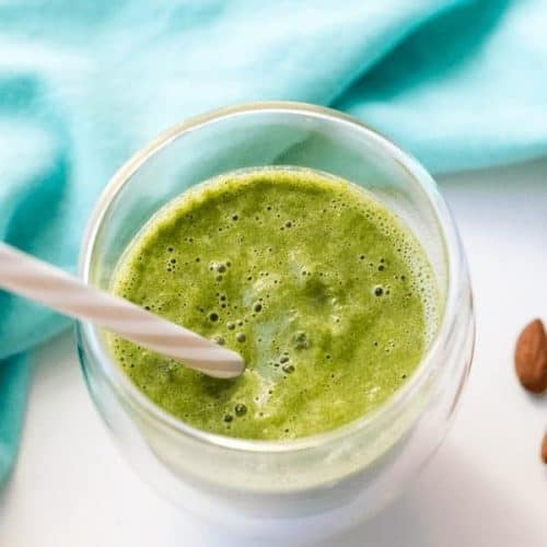 overhead of green smoothie with a straw in it.