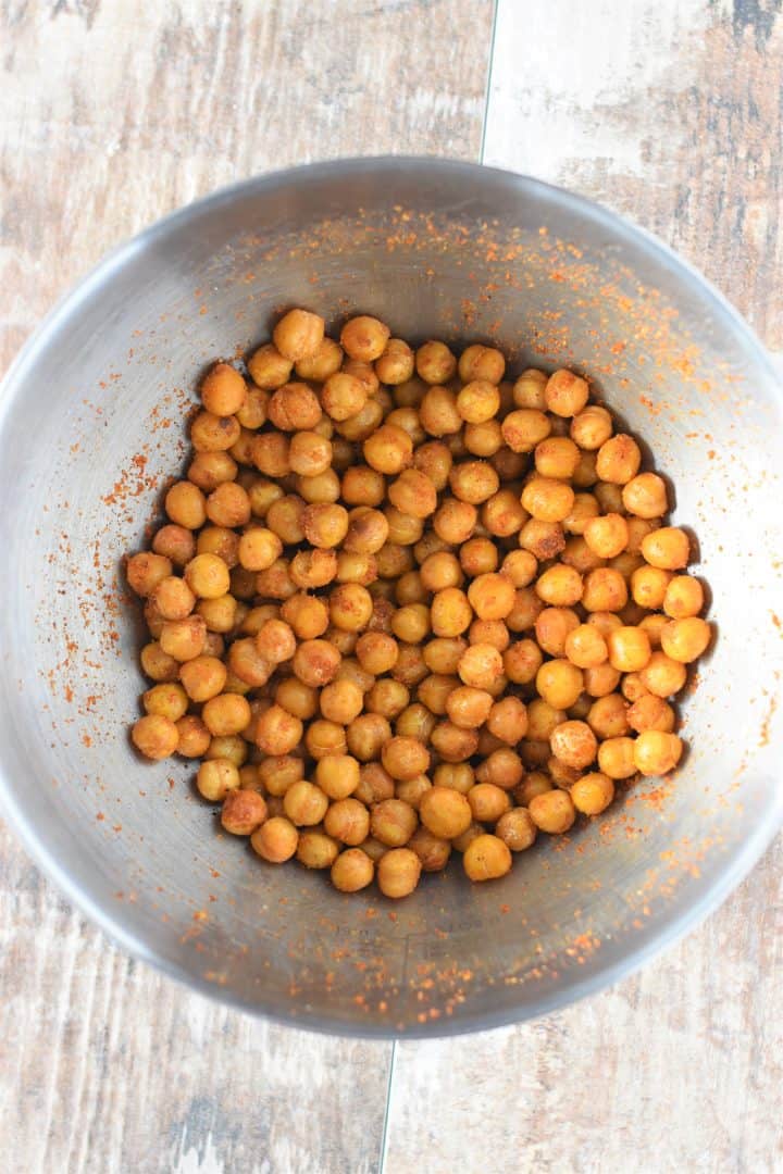 Chickpeas mixed with taco fiesta seasoning in mixing bowl