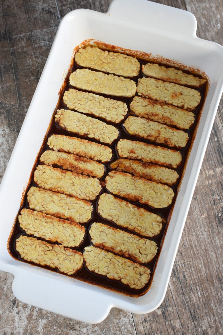 tempeh strips placed in the marinade in the baking dish