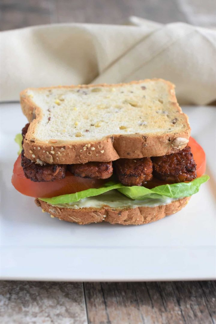 sandwich on a white plate with kitchen napkin behind it