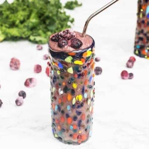 front view of berry avocado smoothie in a colorful glass.