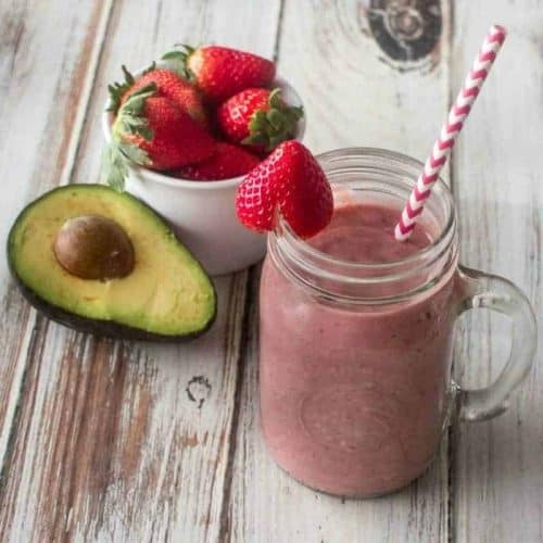 strawberry avocado smoothie in a mason jar with a straw.