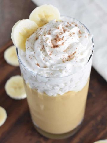 smoothie in a glass topped with non-dairy whipped cream