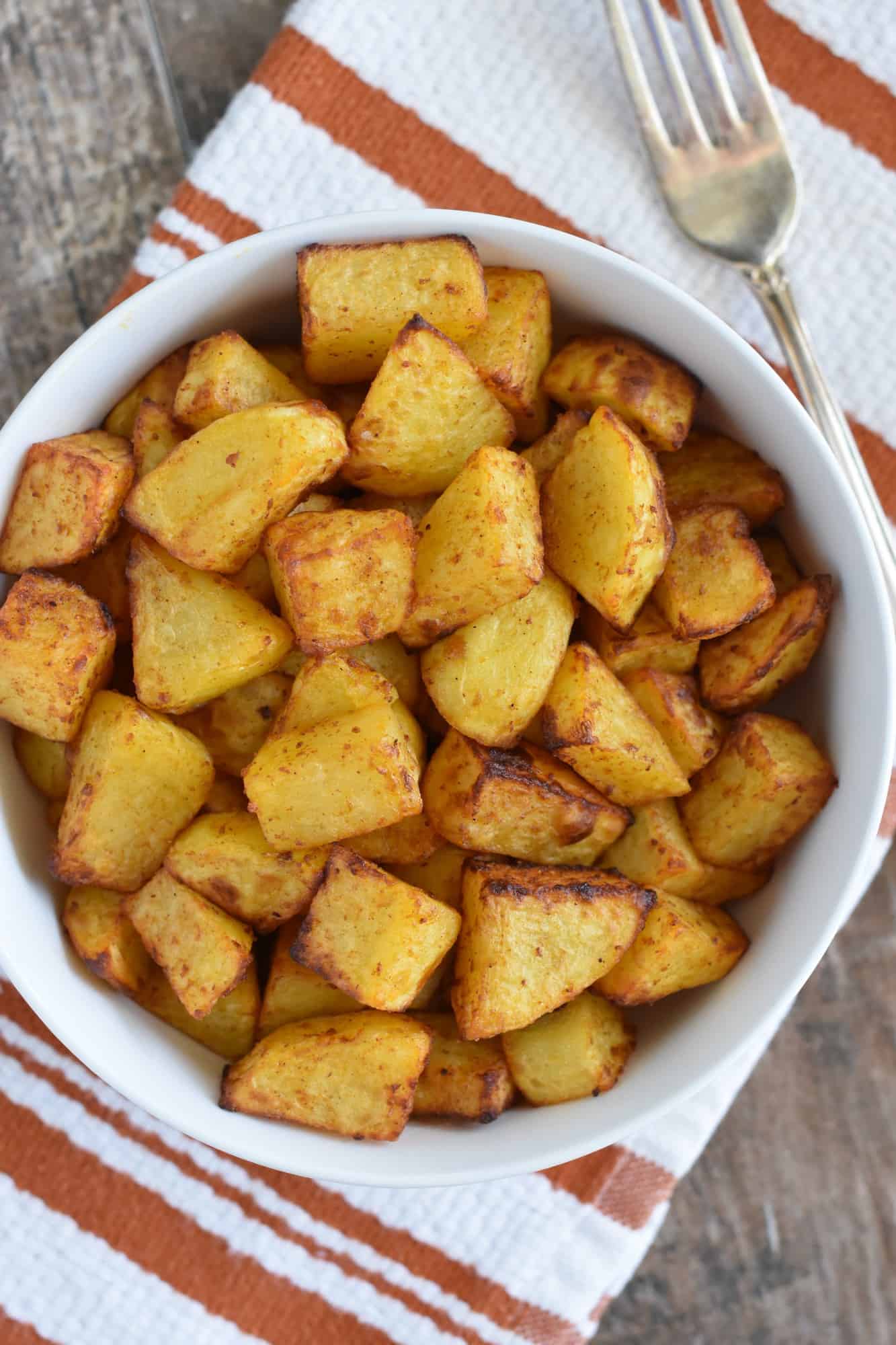 air fryer home fries in white serving bowl with fork next to it