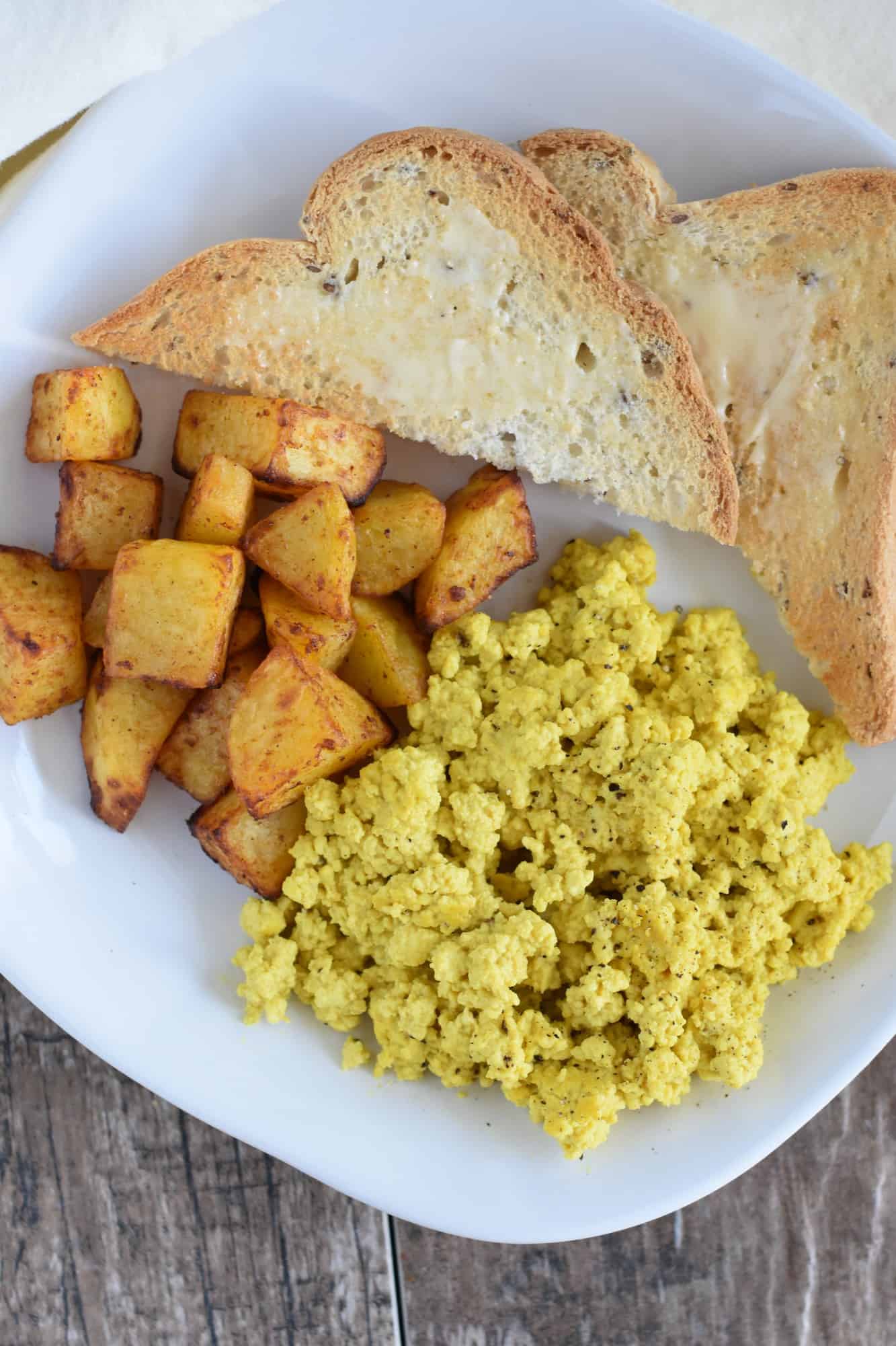 potatoes on a white plate next to tofu scramble and toast