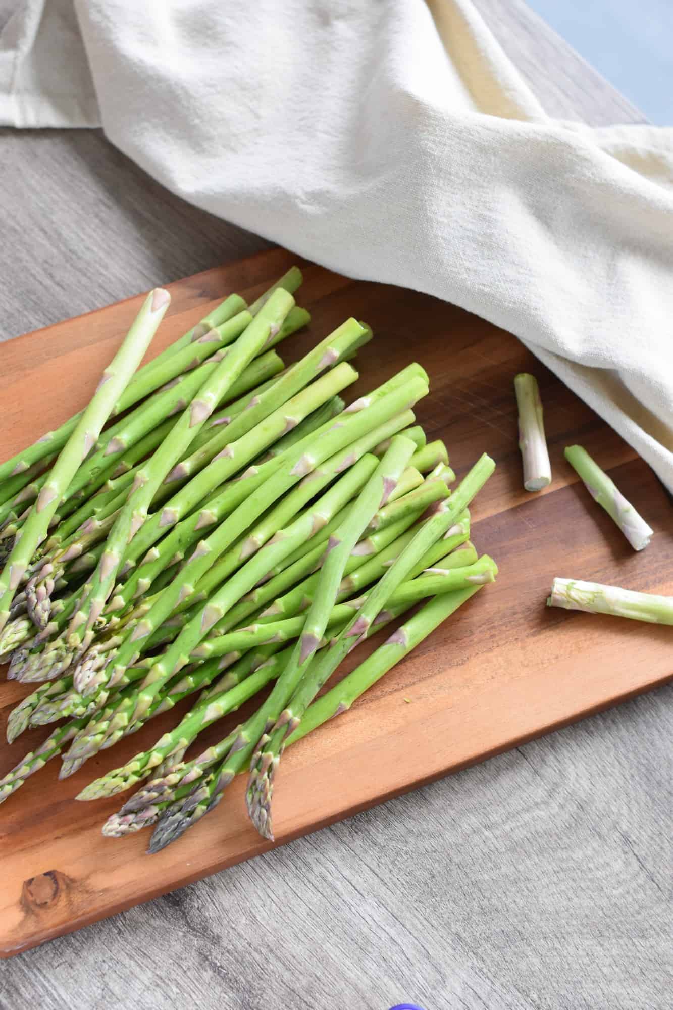 asparagus on cutting board with some of the trimmed ends on the board