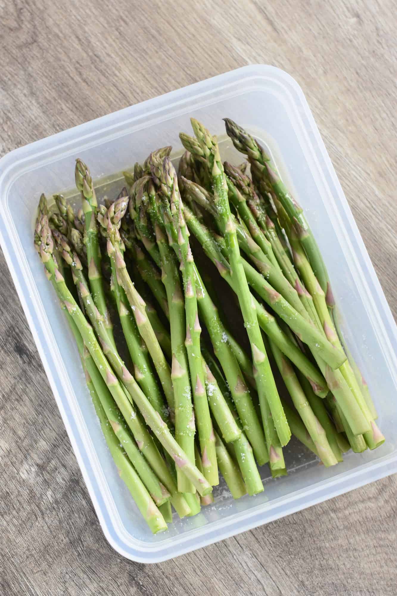 Asparagus in container with olive oil in salt