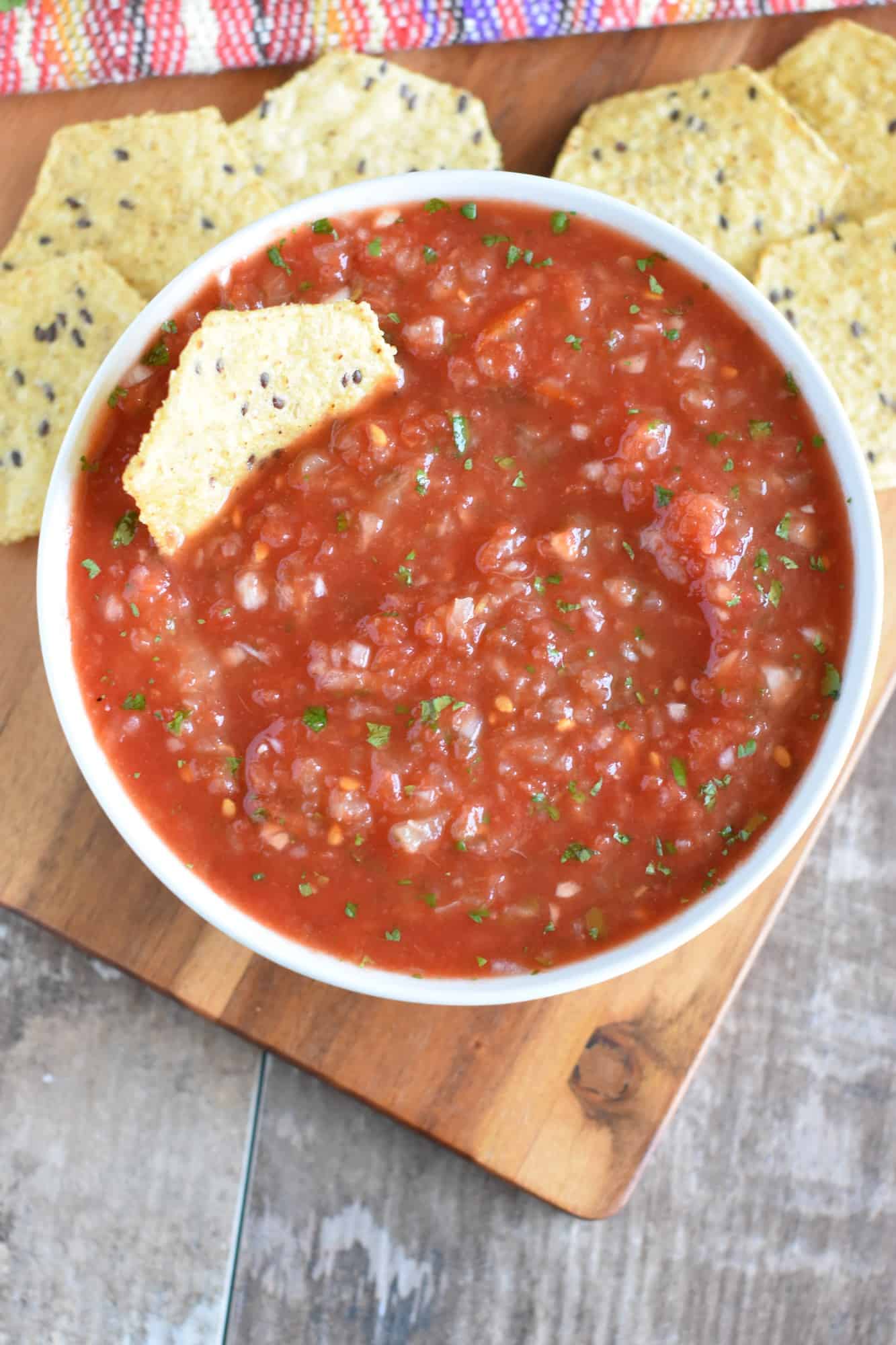 chip stuck in a bowl of salsa with some more chips behind it