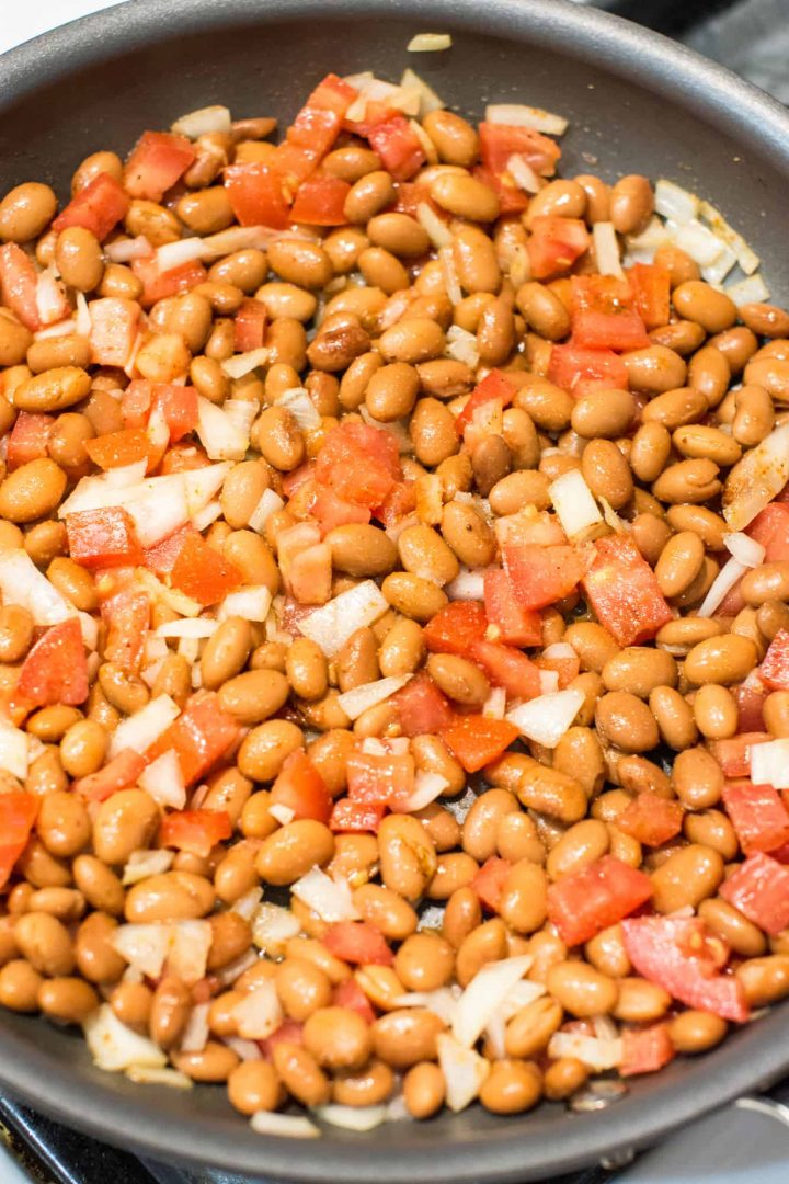 Beans, onions and tomatoes cooking in pan