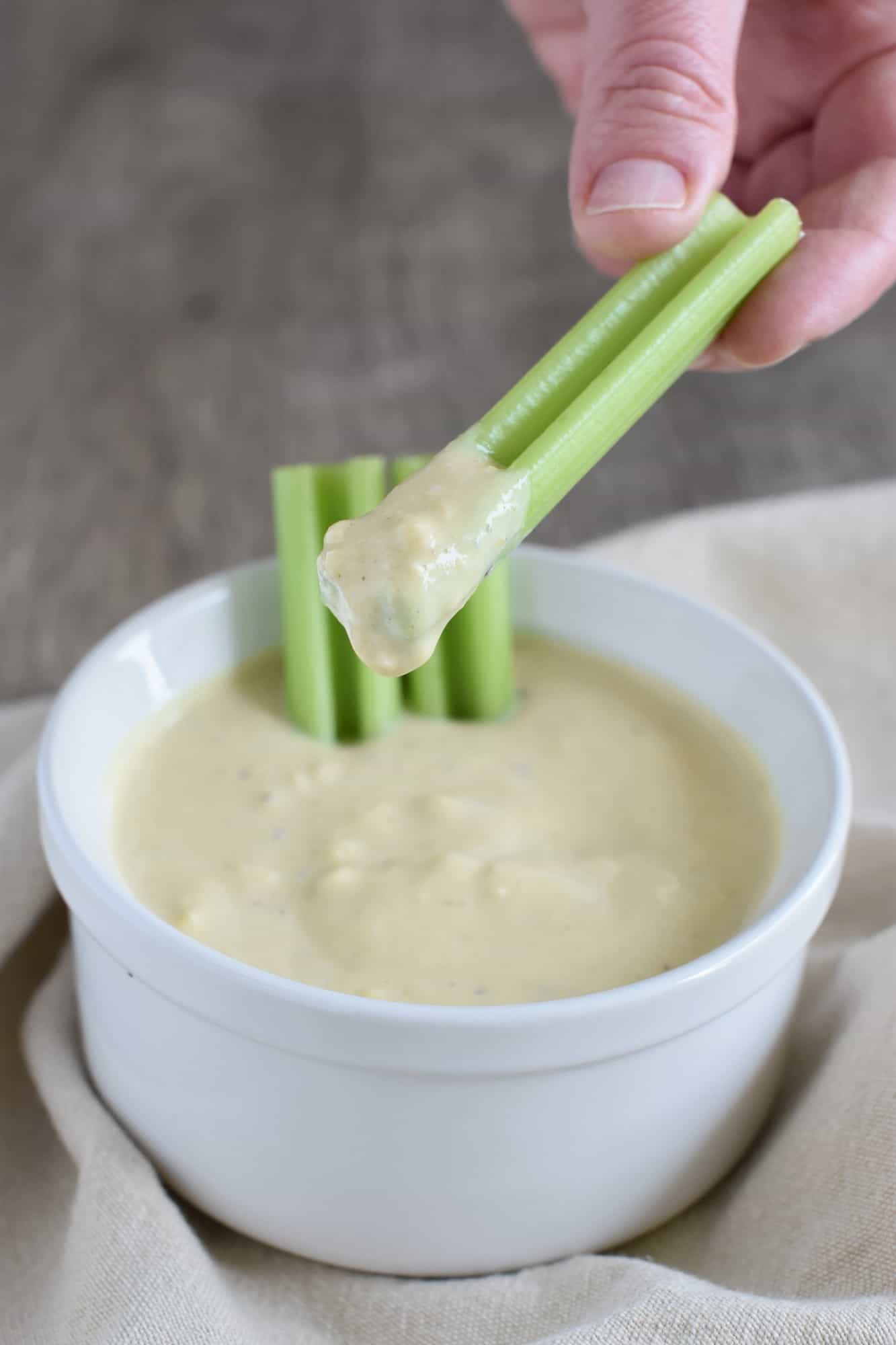 holding a celery stick that was dipped into the dressing