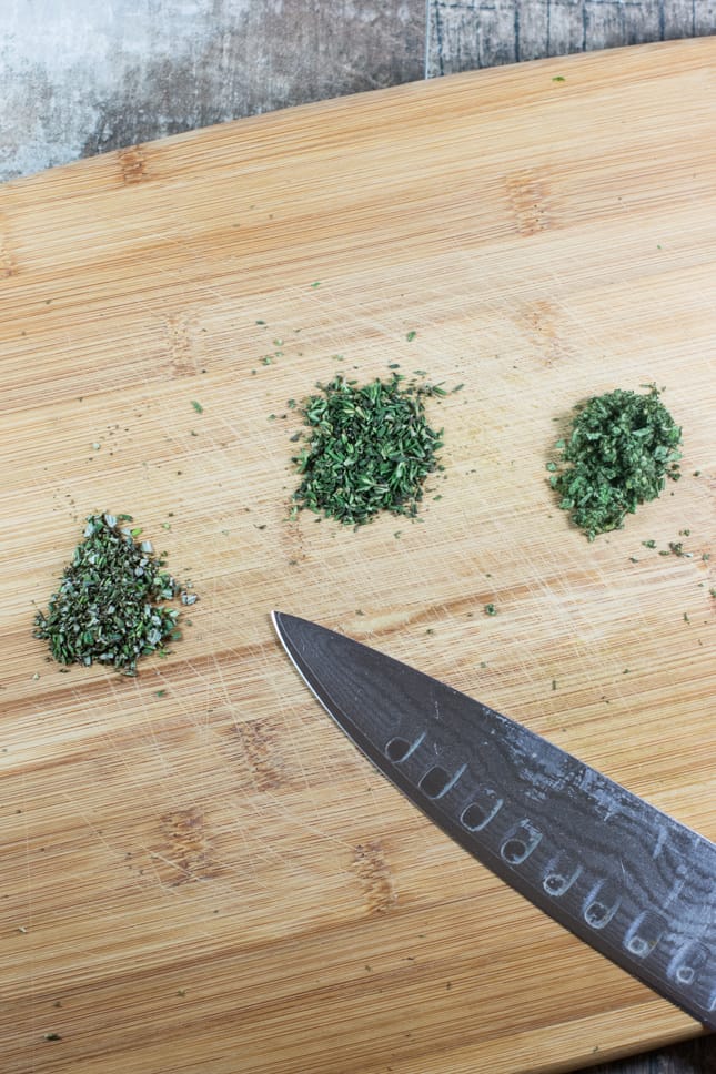 fresh herbs chopped on a cutting board with a knife on it