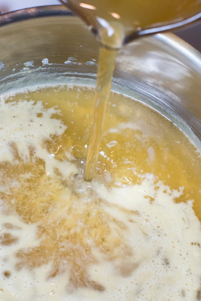 pouring the vegetable broth into the saucepan