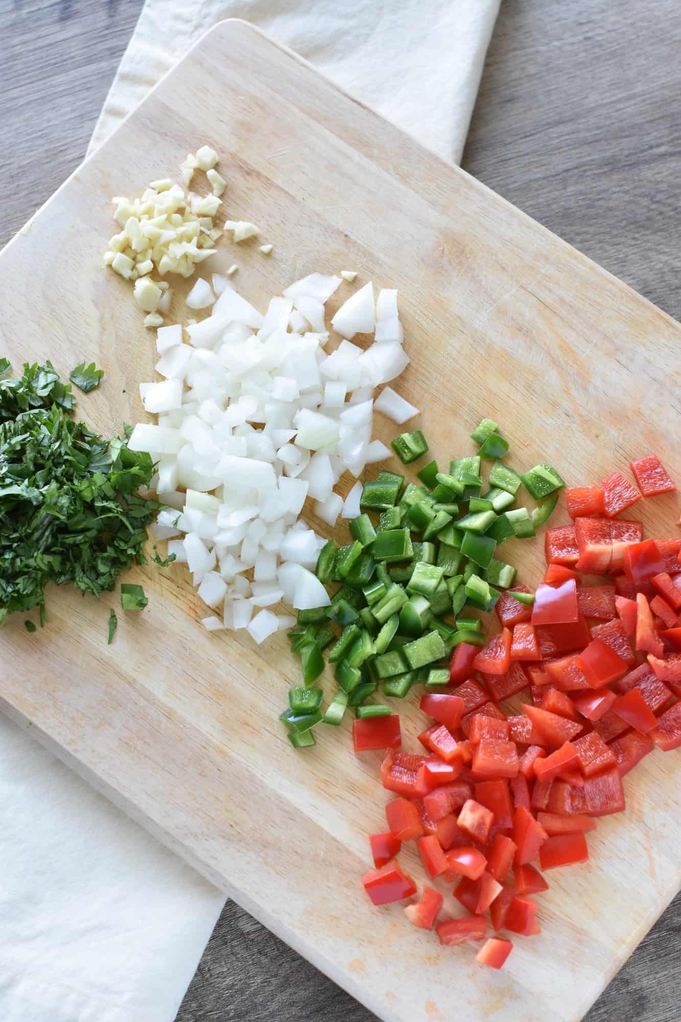 bell pepper, jalapeno, onion, garlic and cilantro chopped on cutting board