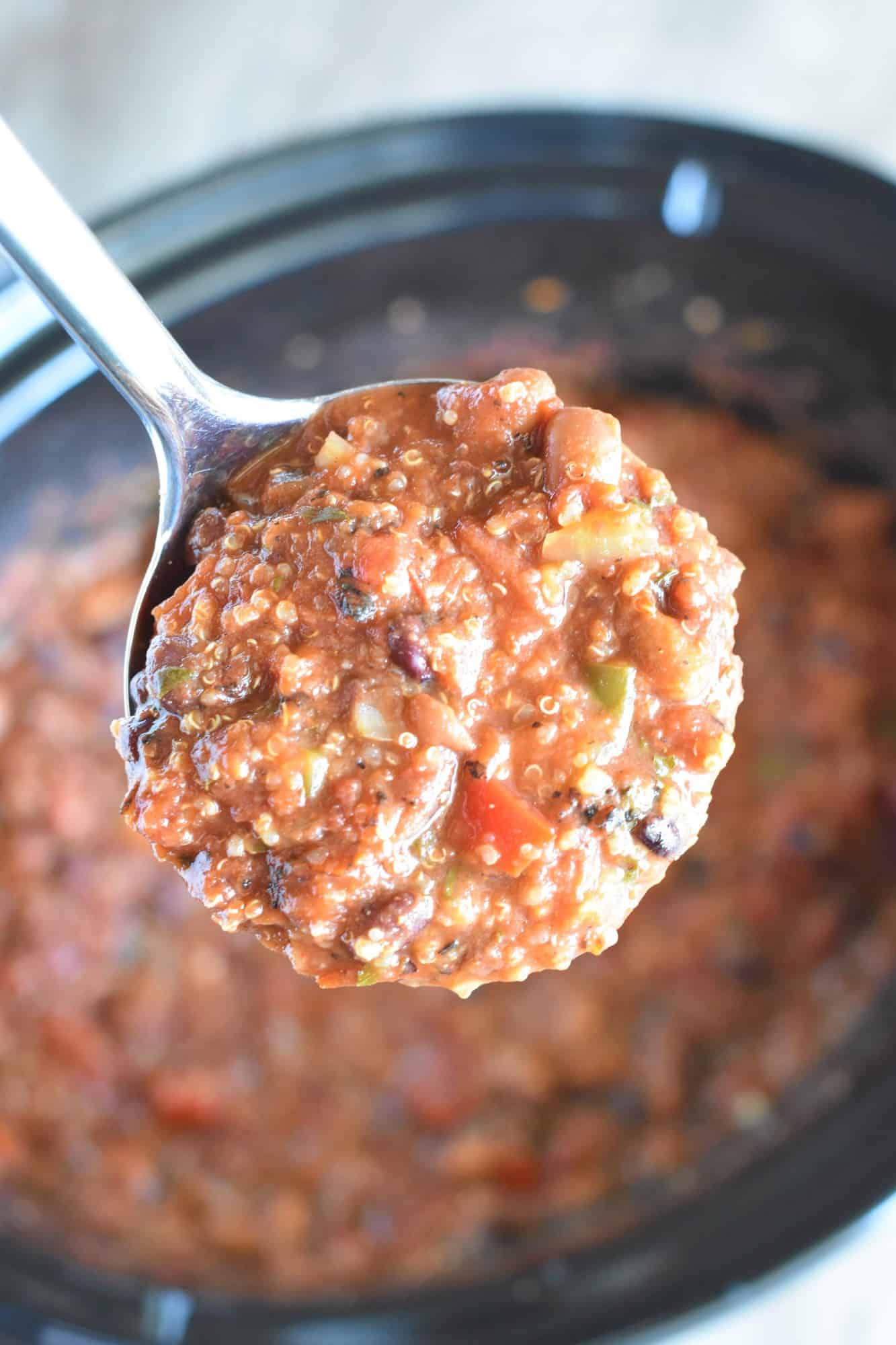 Holding up a ladleful of chili over the cooked chili in the slow cooker