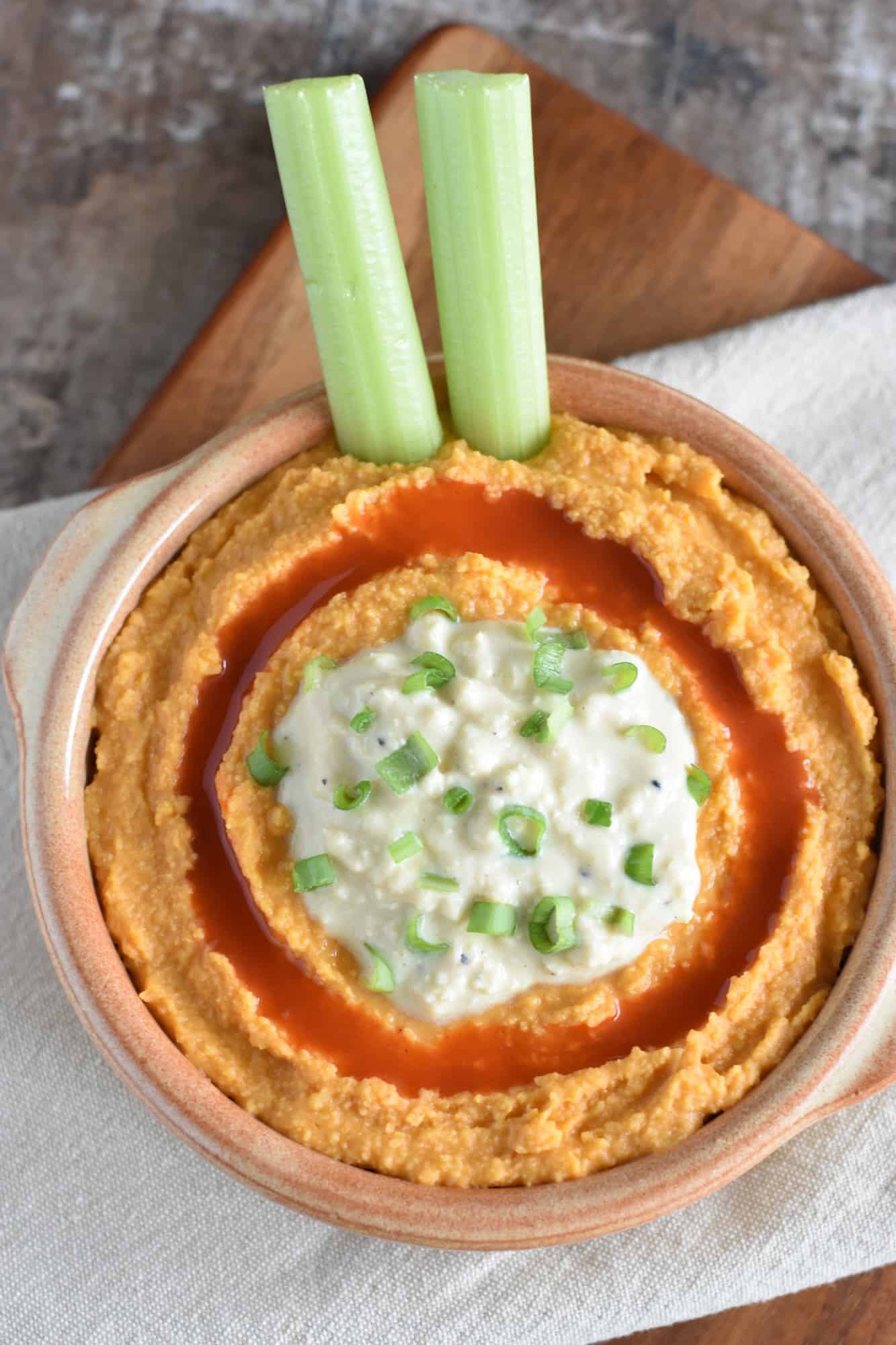 hummus in serving bowl with two celery sticks in it