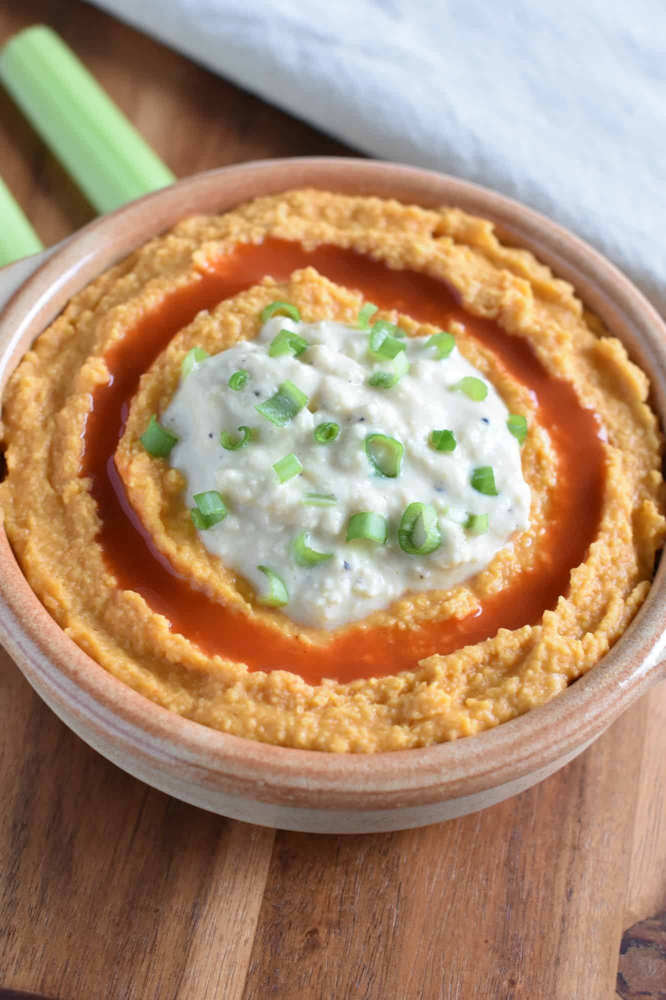 hummus in a serving bowl on a wooden board