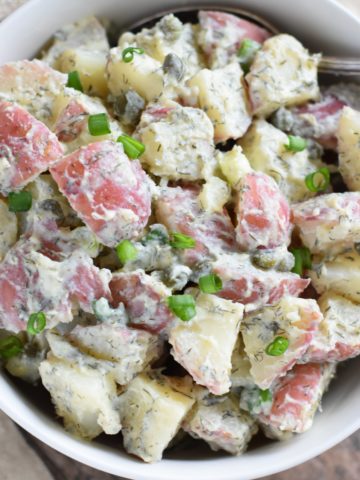 overhead of potato salad in a white bowl with a spoon in it