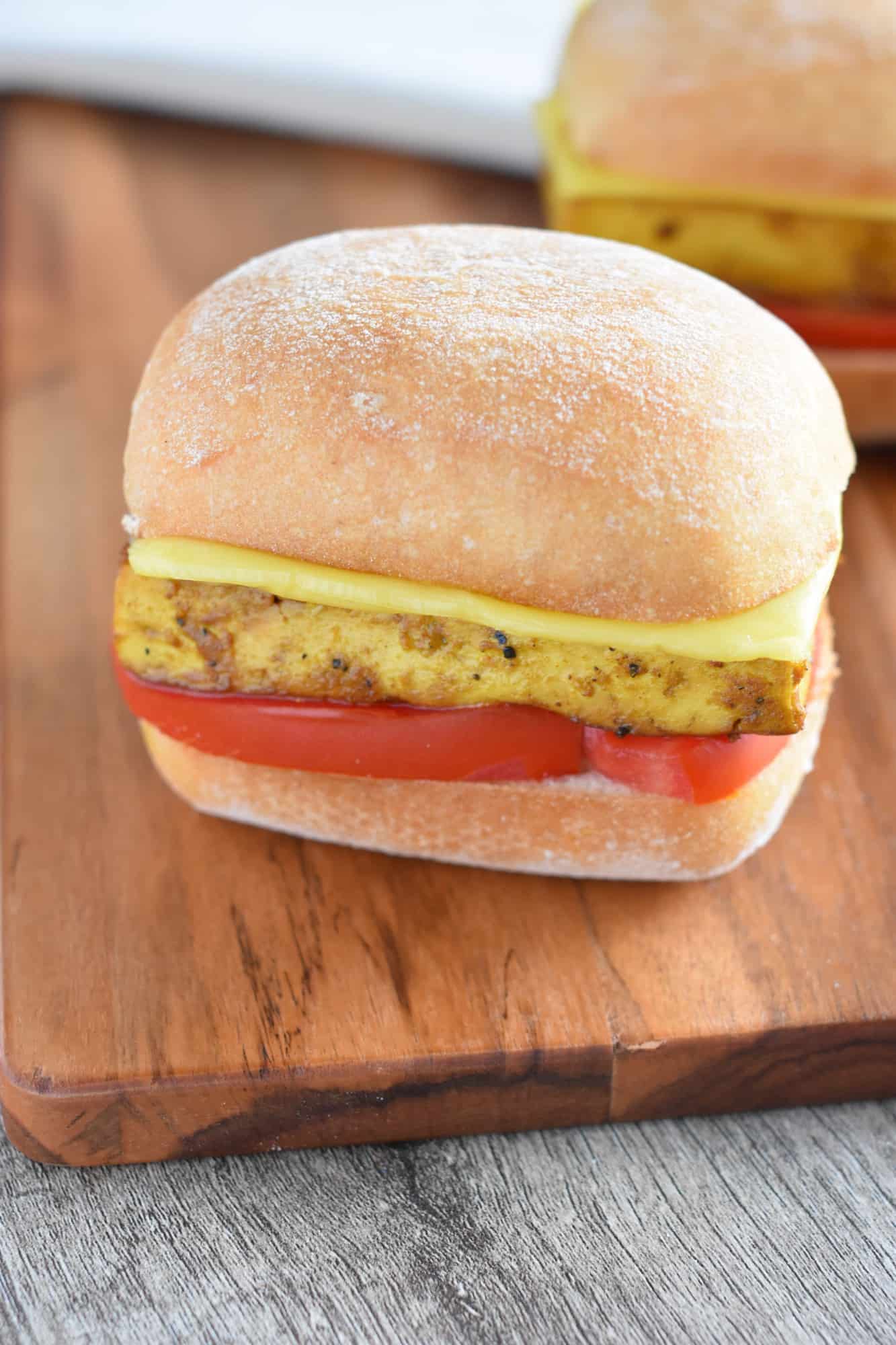 close up of 1 of the sandwiches with one in the background on a wooden board