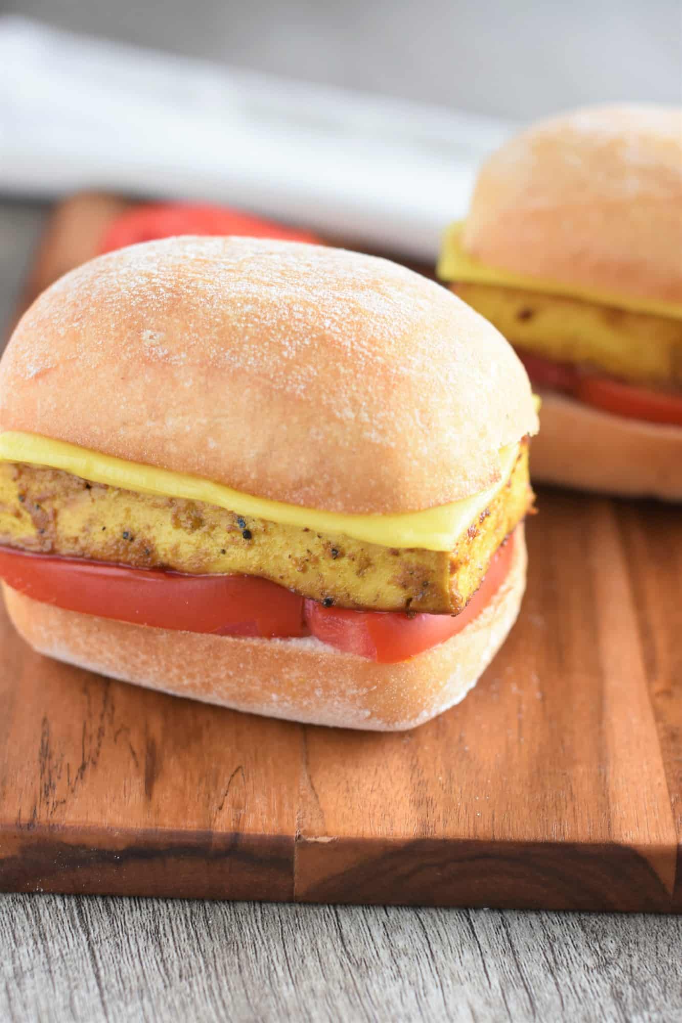 front/side view of a sandwich on a wooden board with one in the background