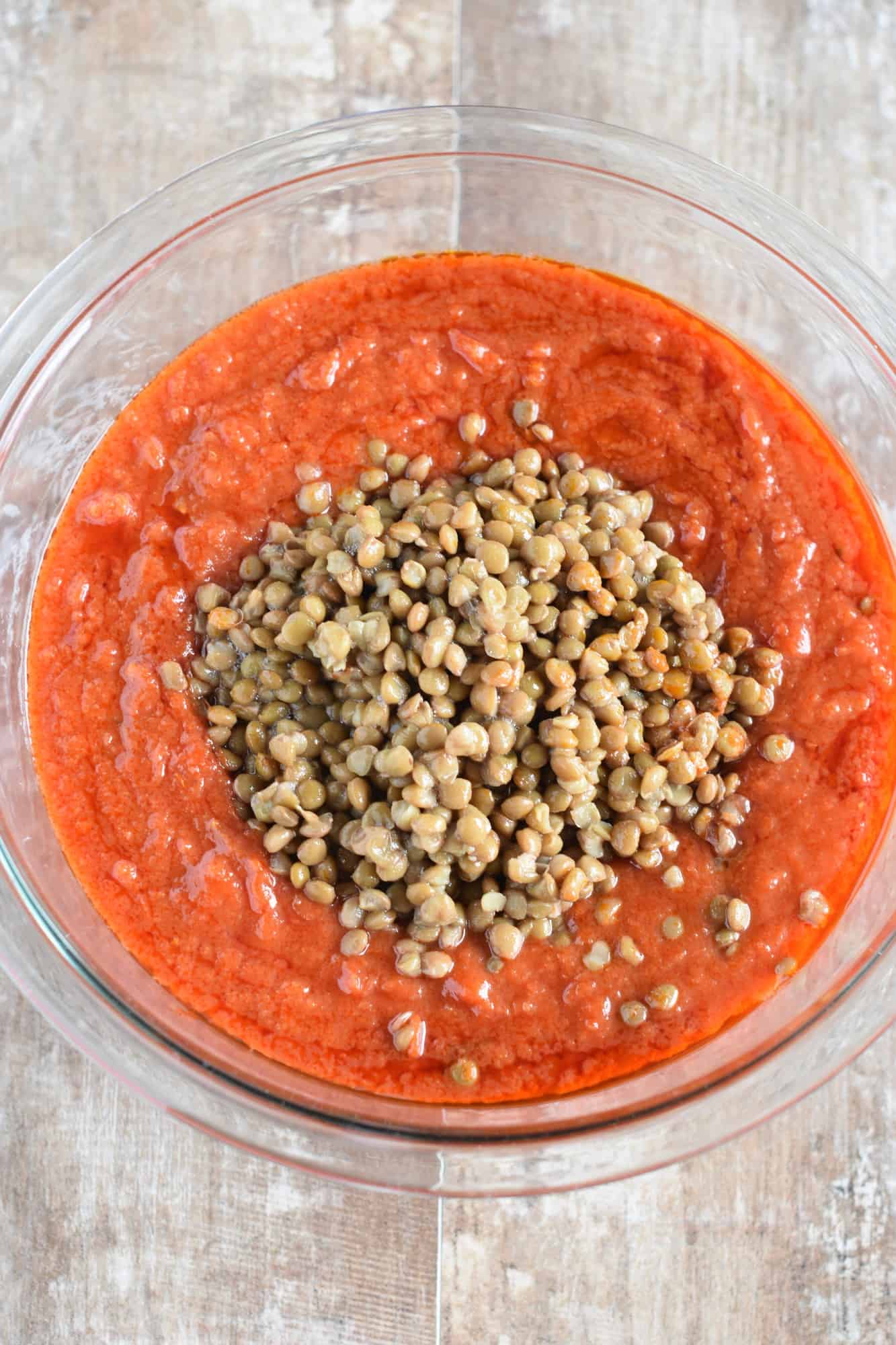 lentils added to pasta sauce in a mixing bowl