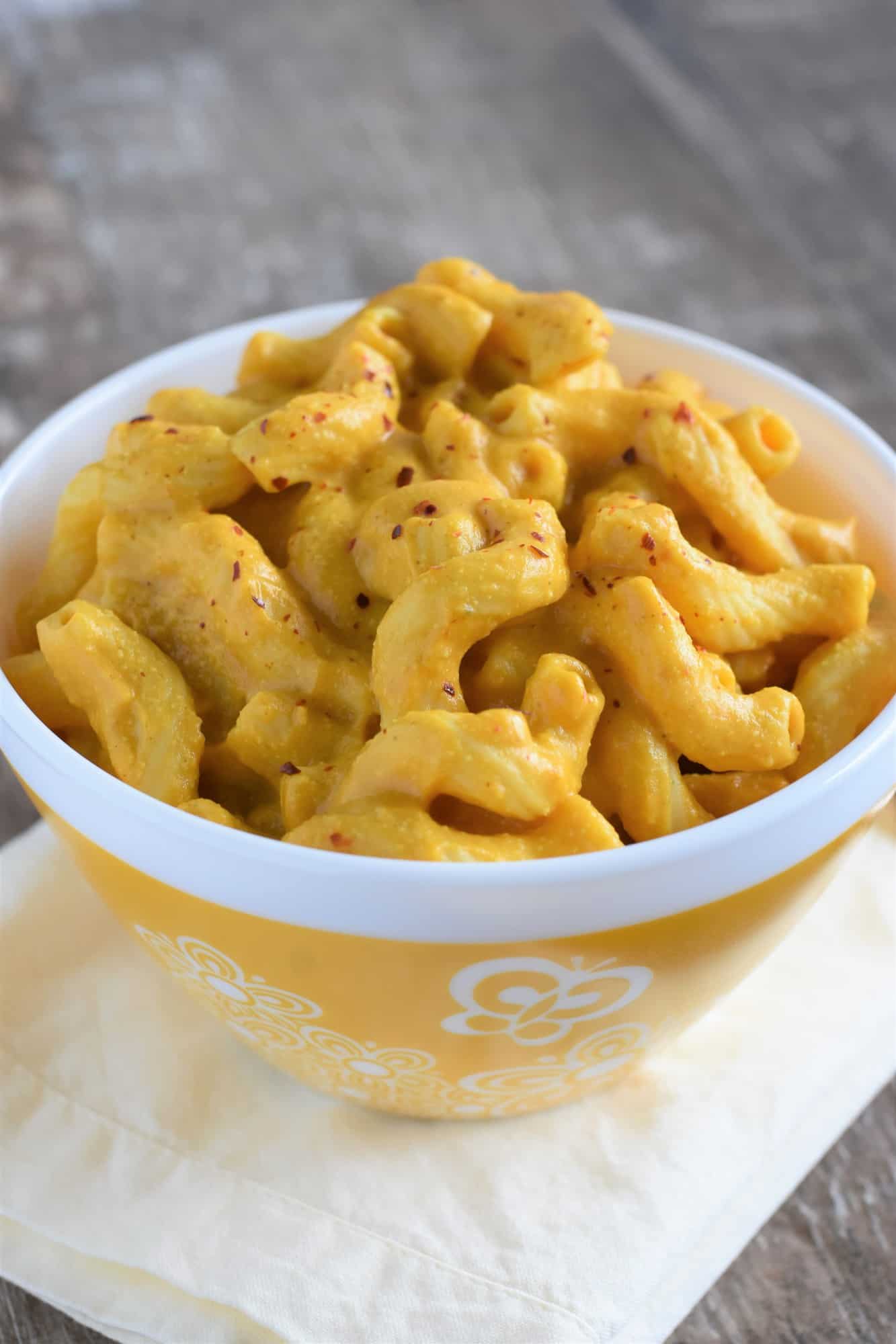 front view of pasta in decorated yellow bowl topped with crushed red pepper flakes