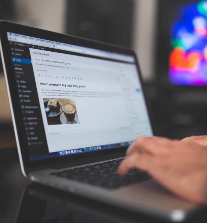 person typing a blog post in WordPress on a laptop