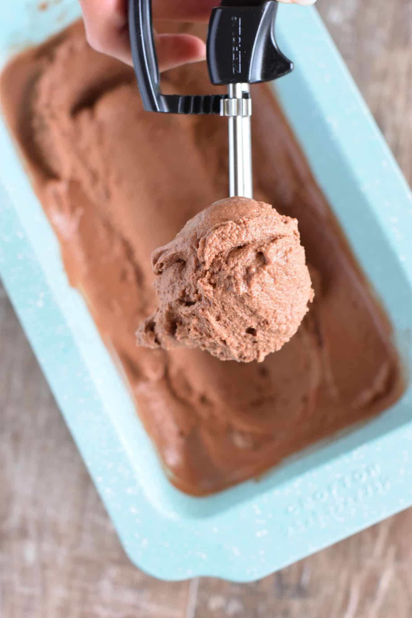 holding a scoop of nice cream in the ice cream scoop over a loaf pan with the rest of it