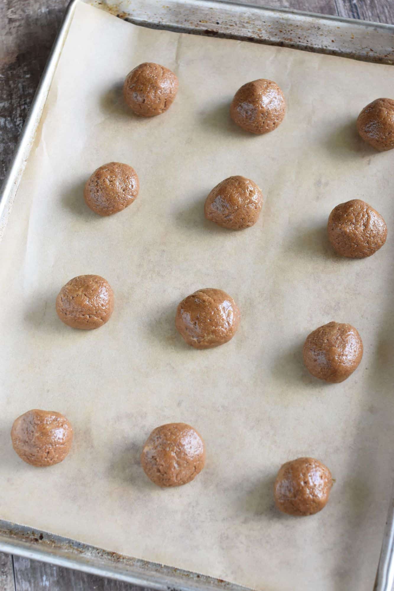 each piece of scooped cookie dough rolled into balls on baking sheet