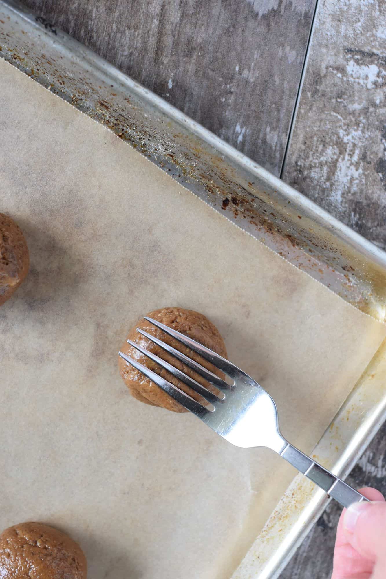 pressing down one of the cookie dough balls with a fork going one way