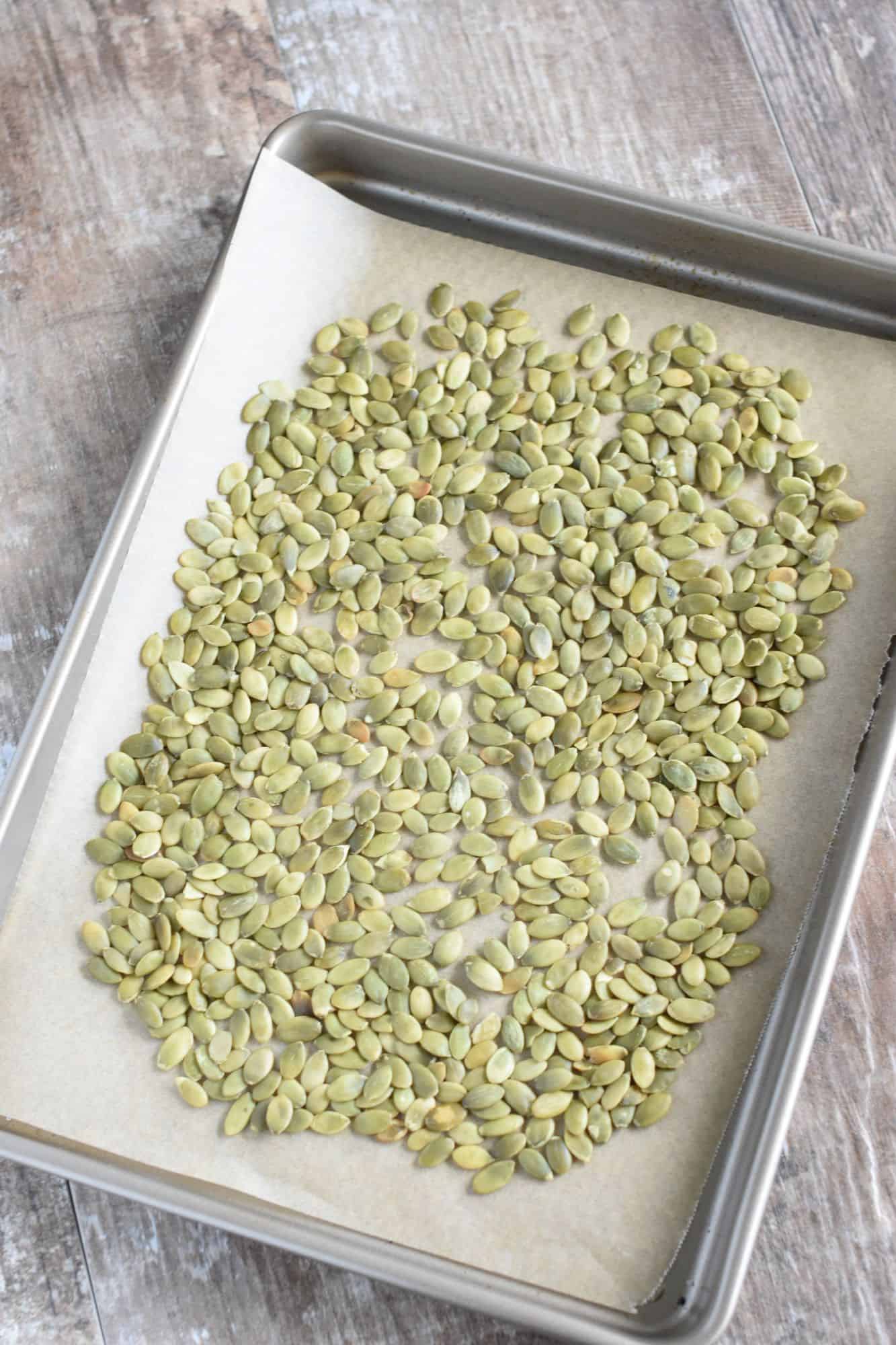 raw pepitas on a parchment-lined baking sheet