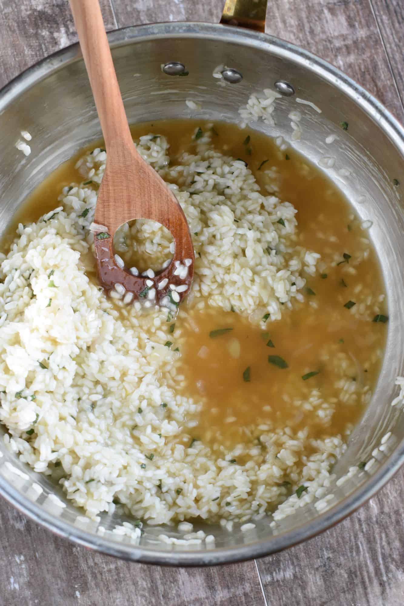 Ladleful of vegetable broth added to the pan