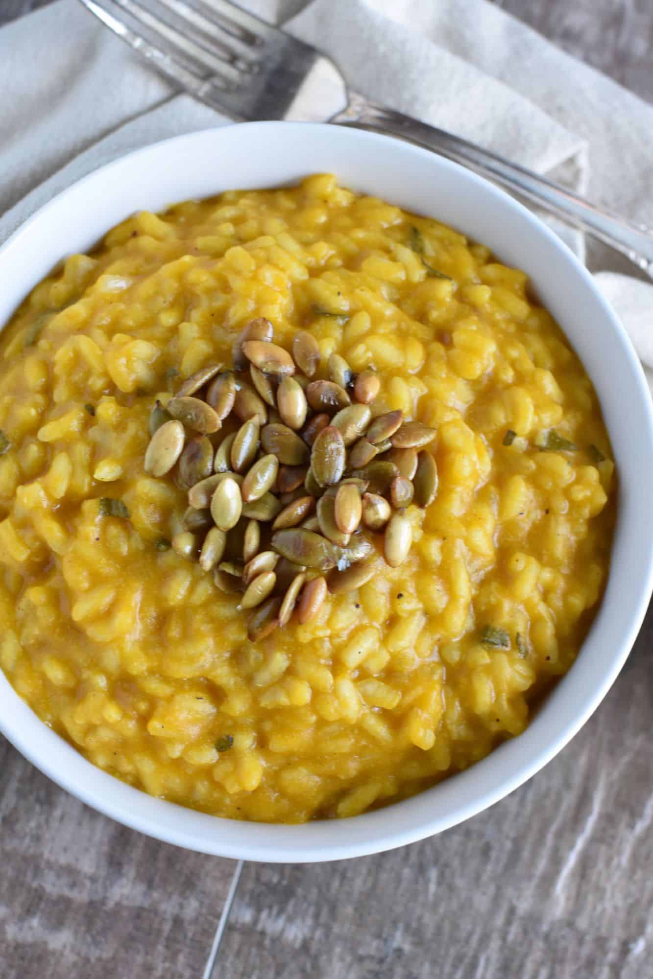 overhead of risotto in a white bowl with some roasted pepitas in the center