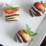 overhead of three strawberries on a white plate