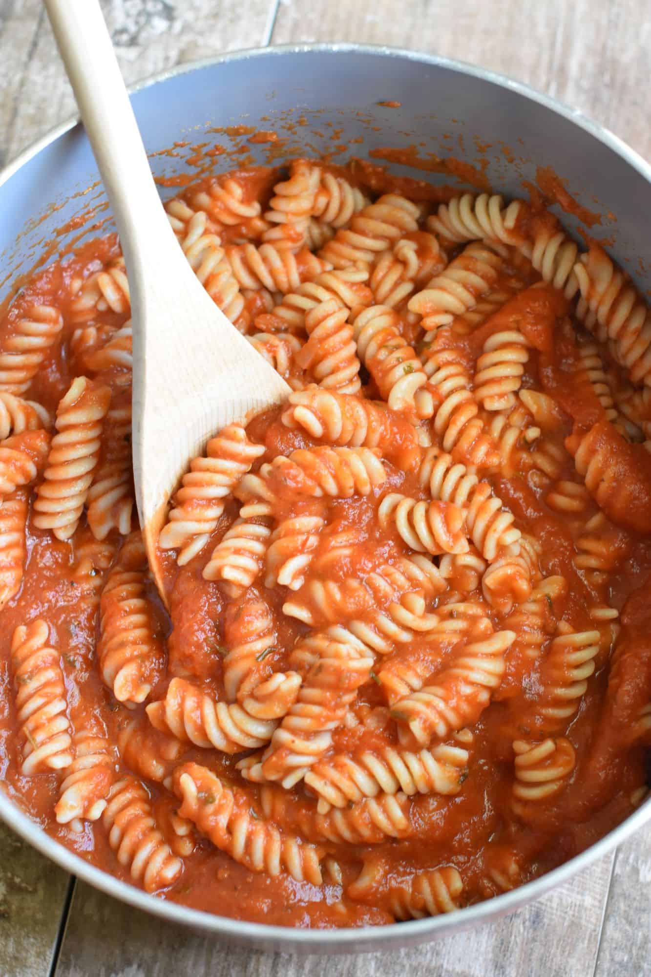 gathering some pasta and sauce with a wooden spoon