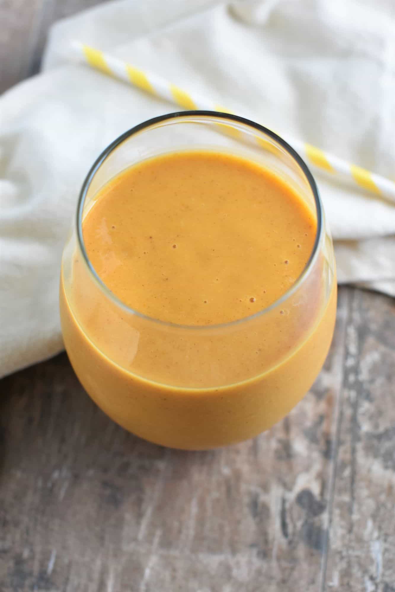 overhead of smoothie in a glass with a straw behind it on a kitchen napkin