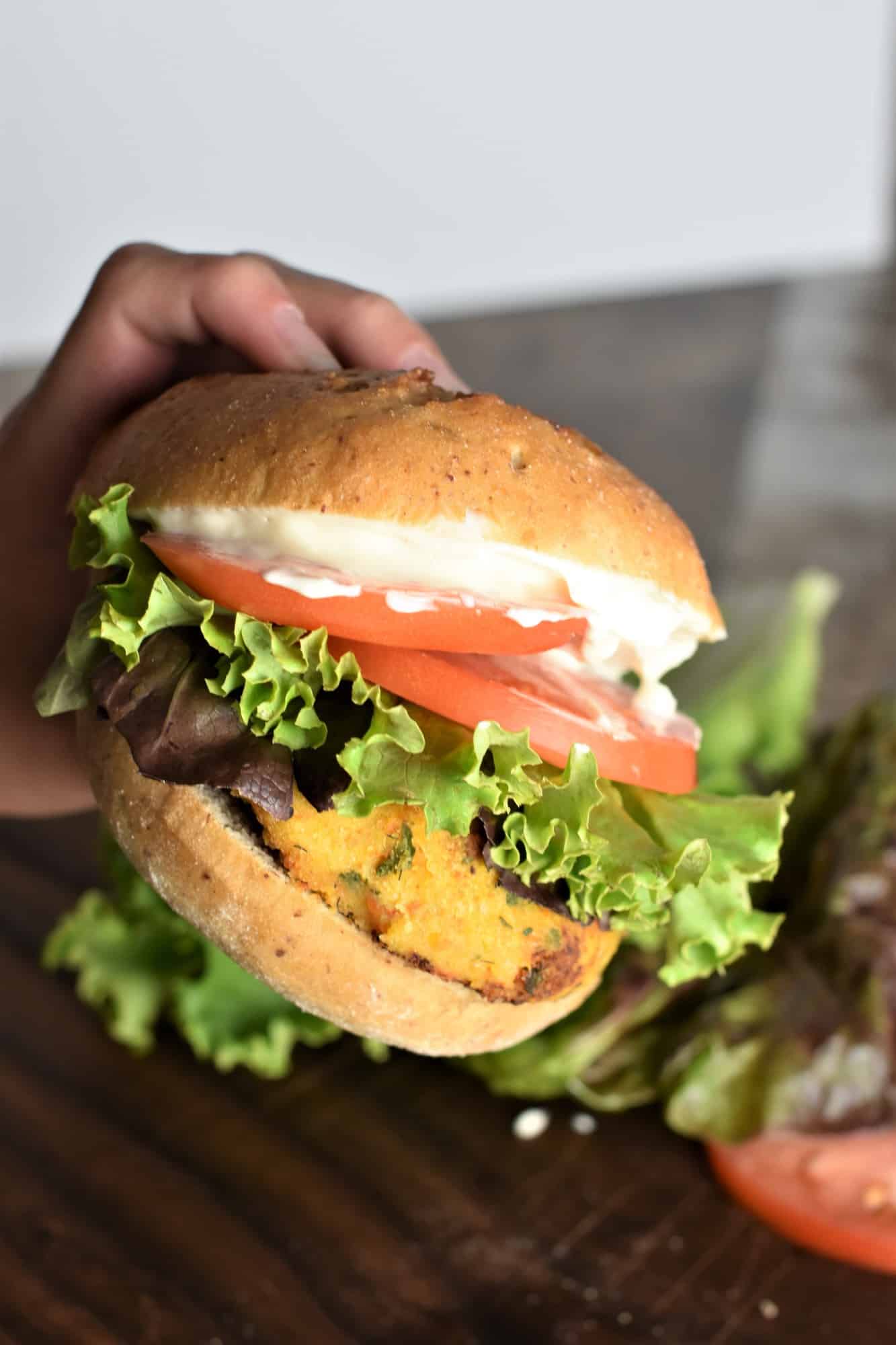 hand holding a burger loaded with toppings