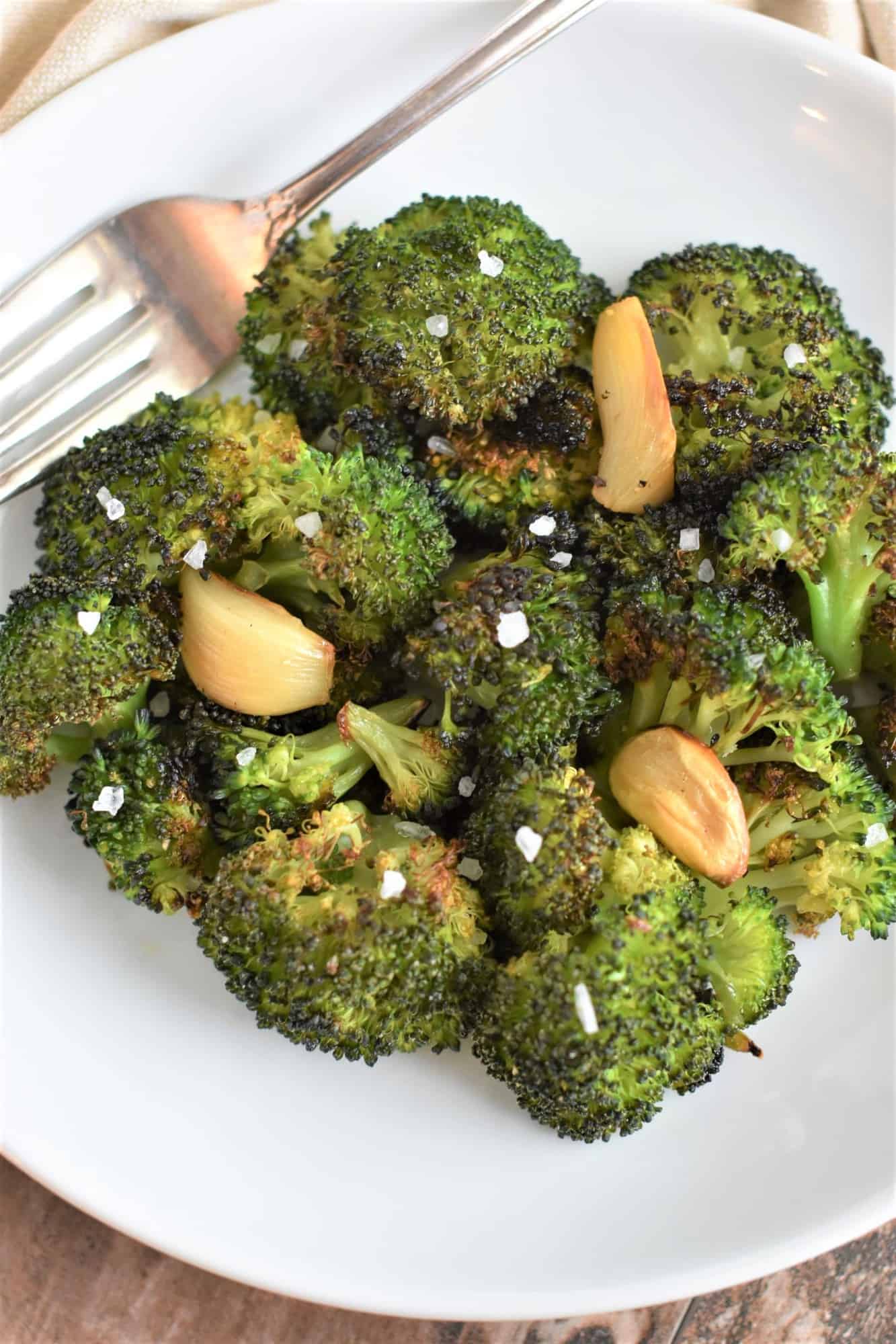 broccoli garnished with coarse sea salt on white plate with fork