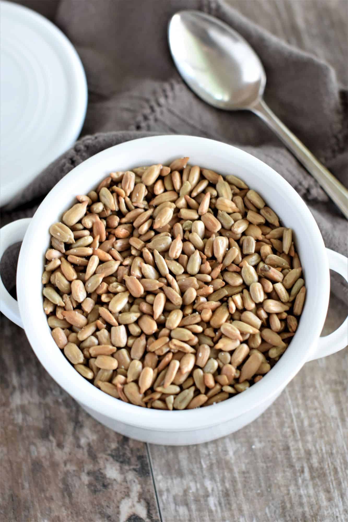 overhead of seeds in white bowl with spoon next to it