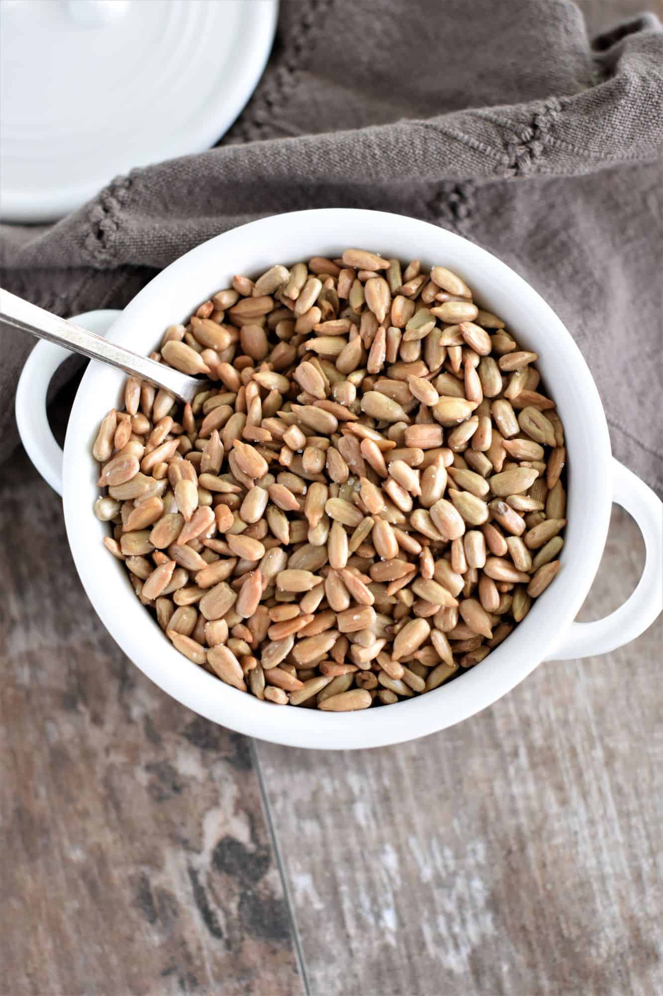 overhead of roasted sunflower seeds in white bowl with spoon