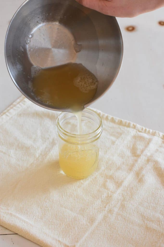 pouring aquafaba into mason jar from mixing bowl