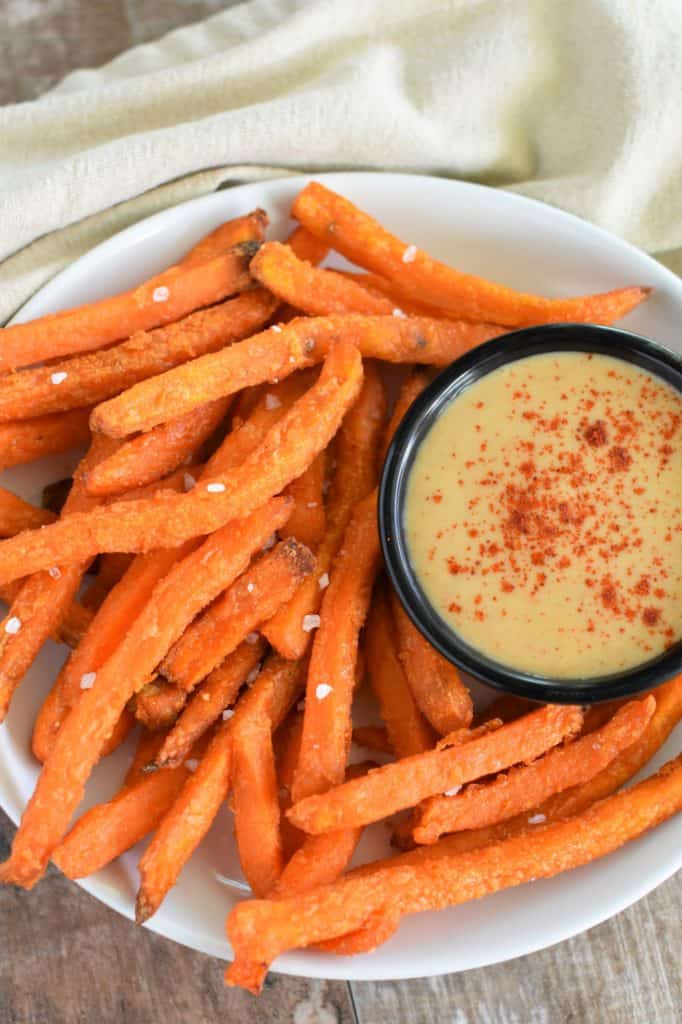 fries on a white plate with a cup of mustard dip on the plate