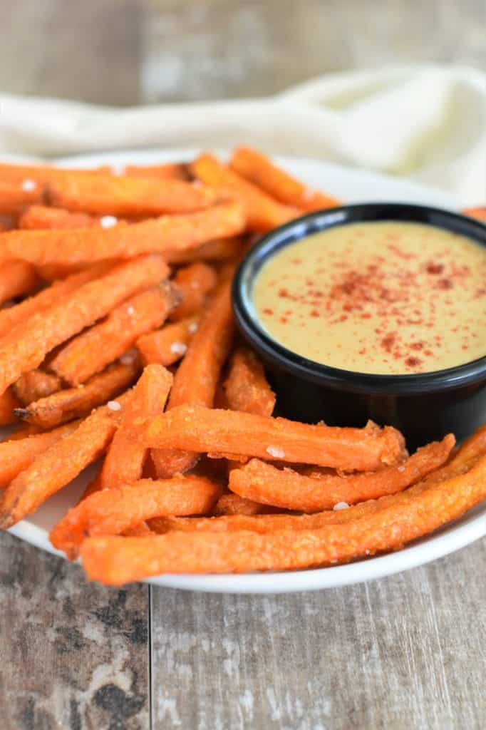 front view of plate of fries with dipping sauce in a small cup