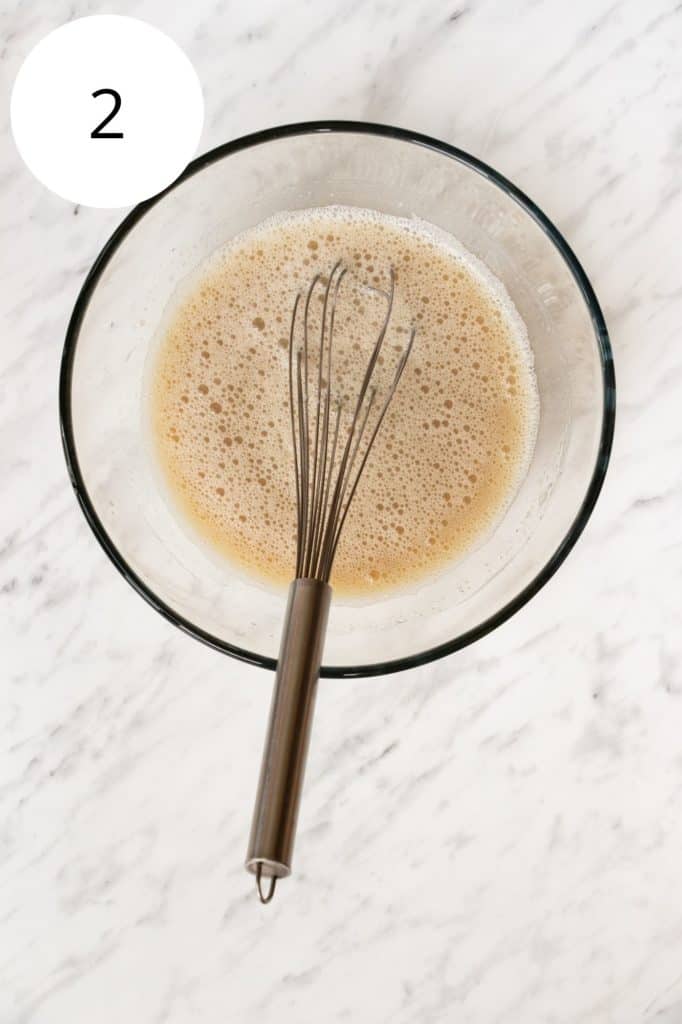 wet ingredients combined in mixing bowl with whisk in it