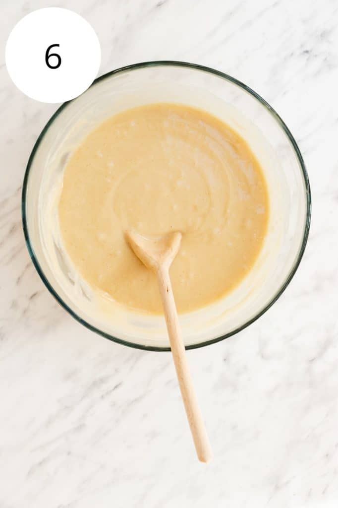 wet and dry ingredients combined in mixing bowl with wooden spoon in it