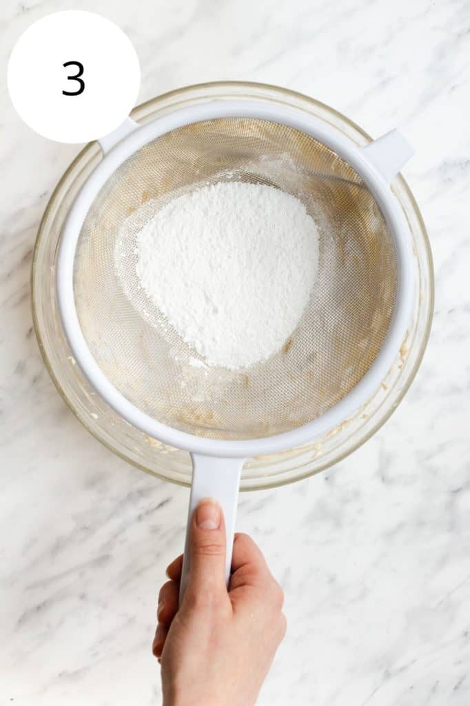 sifting powdered sugar into the mixing bowl