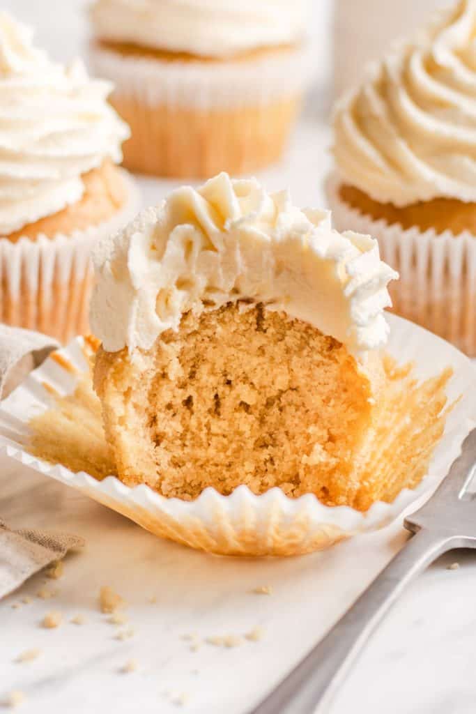 cupcake with a bite taken out on the cupcake wrapper with a fork next to it