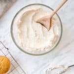 overhead of frosting in mixing bowl with wooden spoon in it